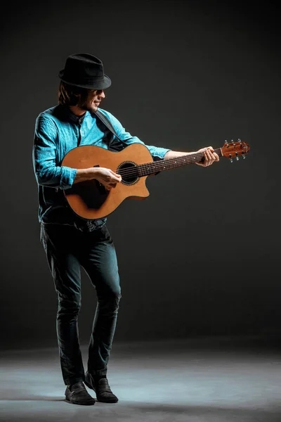 어두운 배경에서 기타와 함께 서 있는 멋진 남자 — 스톡 사진