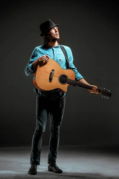 Cool guy standing with guitar on dark background — Stock Photo, Image