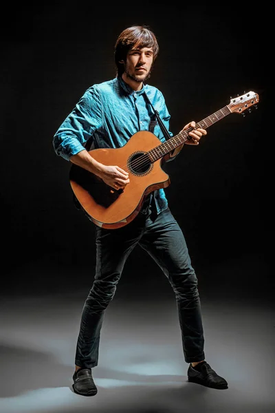 Cool guy standing with guitar on dark background — Stock Photo, Image