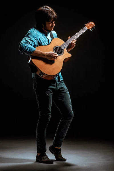 Cool guy standing with guitar on dark background — Stock Photo, Image