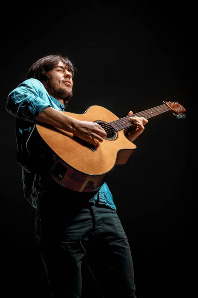 Cool guy standing with guitar on dark background — Stock Photo, Image