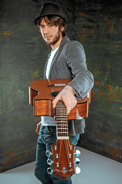 Tipo fresco de pie con la guitarra sobre fondo gris — Foto de Stock