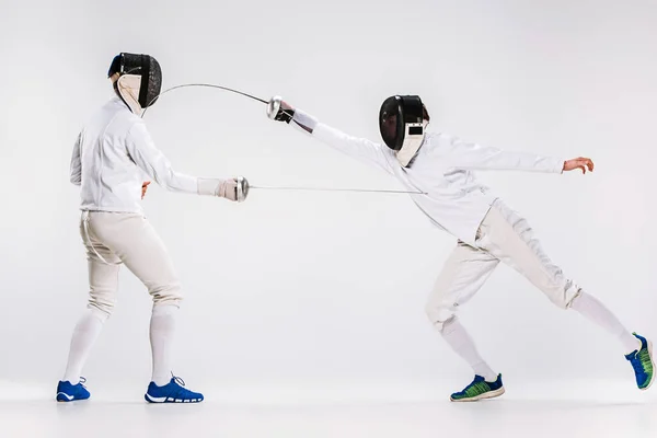 フェンシングを身に着けている二人の男に合わせてグレーに対して剣で練習 — ストック写真