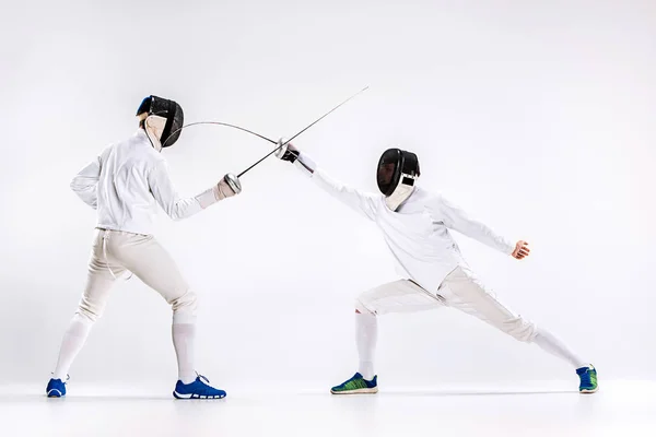 Los dos hombres con traje de esgrima practicando con espada contra gris — Foto de Stock