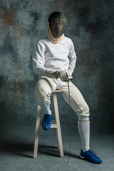 El hombre con traje de esgrima con espada contra gris — Foto de Stock