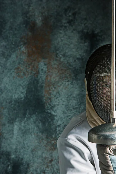El hombre con traje de esgrima con espada contra gris —  Fotos de Stock
