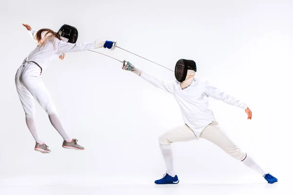 La femme et l'homme portant un costume d'escrime pratiquant avec épée contre le gris — Photo