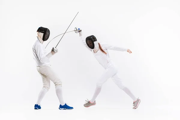 La mujer y el hombre con traje de esgrima practicando con espada contra gris — Foto de Stock