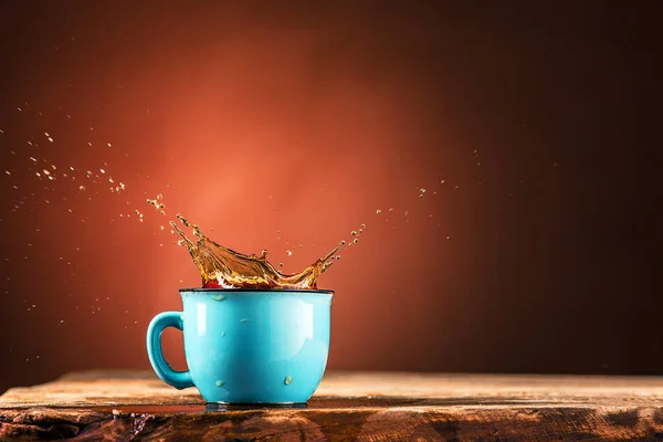 Коричневый брызгает из чашки чая на коричневом фоне — стоковое фото