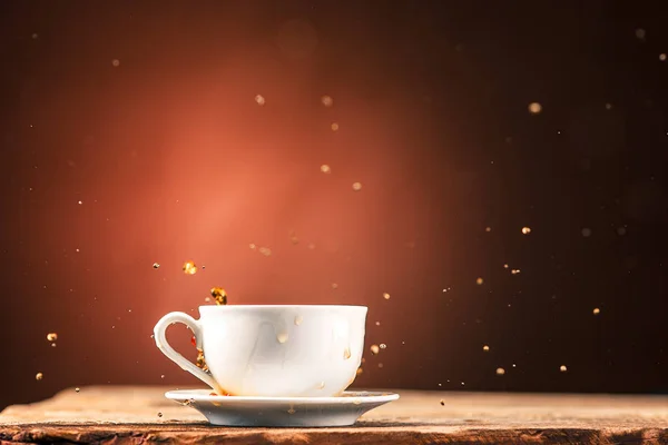 Коричневый брызгает из чашки чая на коричневом фоне — стоковое фото