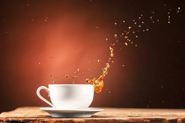 Καφέ πιτσιλιές από ποτό από φλιτζάνι τσάι σε ένα καφέ φόντο — Φωτογραφία Αρχείου