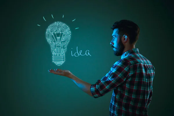 Handsome young man with idea bulb on blue — Stock Photo, Image