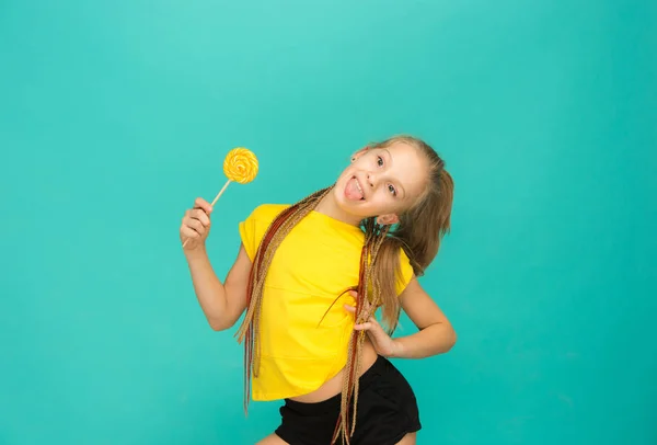 Девушка-подросток с разноцветным леденцом на синем фоне — стоковое фото