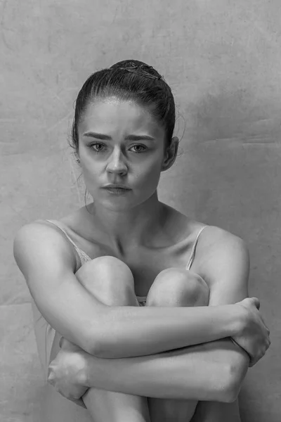 Müde Balletttänzerin sitzt auf dem Holzboden vor rosa Hintergrund — Stockfoto