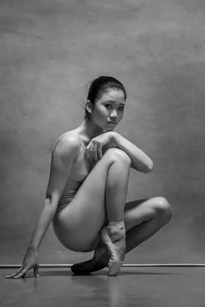 Danseuse de ballet fatiguée assise sur la chaise en bois sur un fond gris — Photo