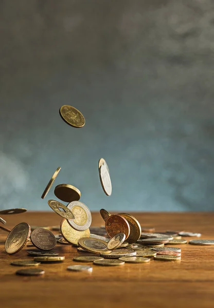 Az ezüst és arany érmék és a leeső érmék, fából készült háttér — Stock Fotó
