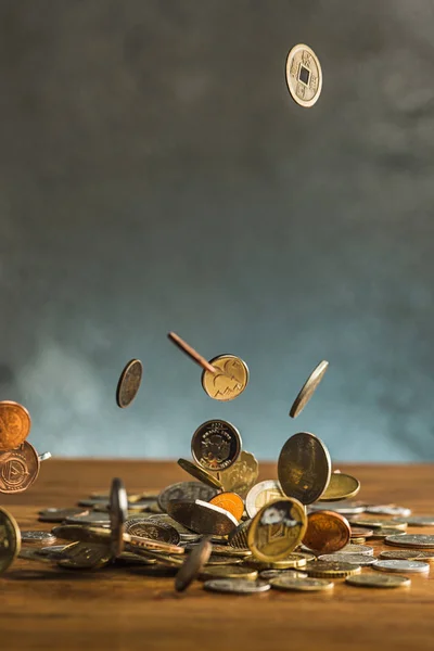 Серебряные и золотые монеты и падающие монеты на деревянном фоне — стоковое фото