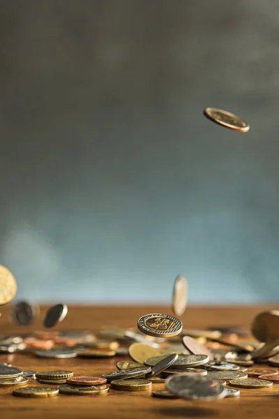 Az ezüst és arany érmék és a leeső érmék, fából készült háttér — Stock Fotó