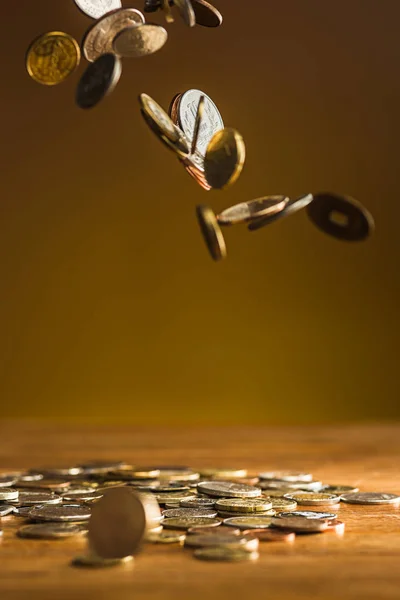 Srebrne i złote monety i monety spadające na podłoże drewniane — Zdjęcie stockowe