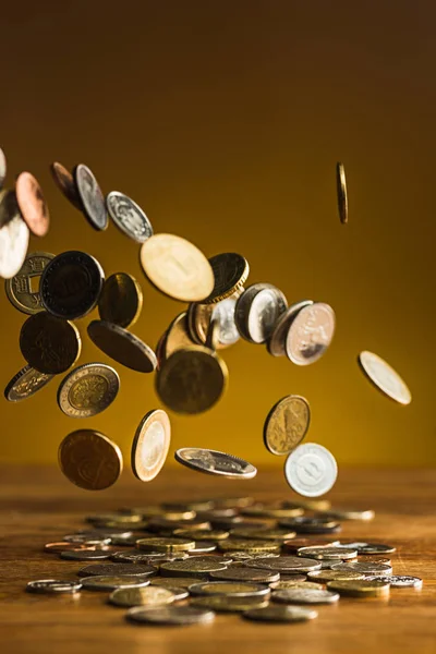 Las monedas de plata y oro y las monedas que caen sobre fondo de madera — Foto de Stock