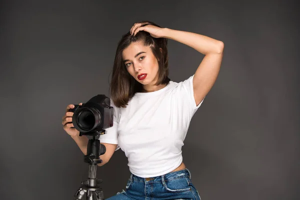 Portrét mladé ženy s kamerou na šedém pozadí — Stock fotografie