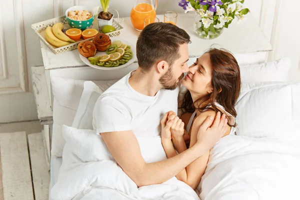 Mladý dospělý heterosexuální pár ležící na posteli v ložnici — Stock fotografie