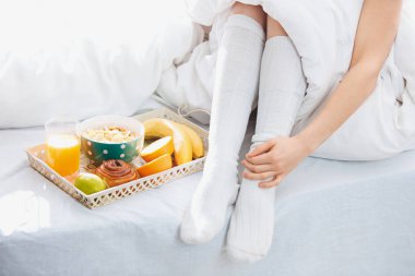 Yatakta kadın bacakları ve kahvaltı kısmi görünümü