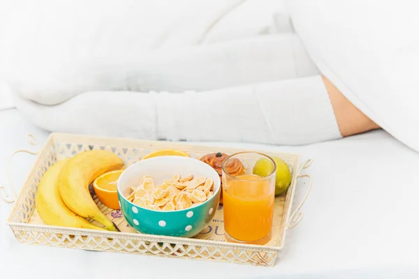 Delvis skymd utsikt över kvinnliga ben och frukost på sängen — Stockfoto