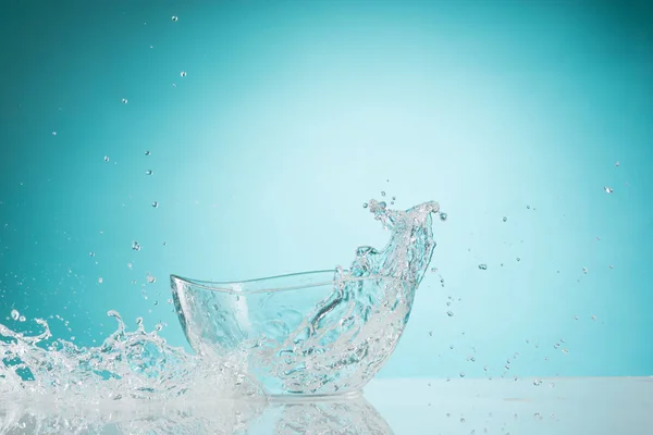 A água salpicando para tigela de vidro no fundo branco — Fotografia de Stock