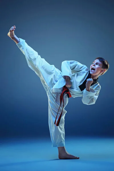 Young boy training karate on blue background — Stock Photo, Image