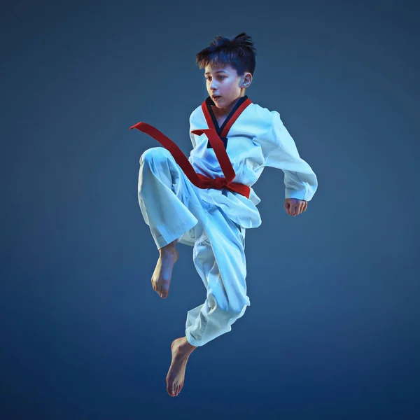 Fiatal fiú képzés karate-kék háttér — Stock Fotó