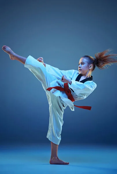 Chica joven entrenando karate sobre fondo azul — Foto de Stock