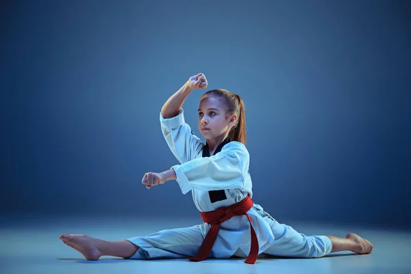 Chica joven entrenando karate sobre fondo azul — Foto de Stock