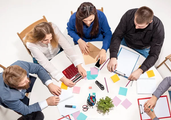 Team sitzt hinter Schreibtisch, prüft Berichte, spricht. Ansicht von oben — Stockfoto