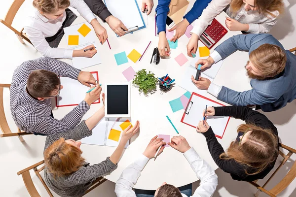 Equipo sentado detrás del escritorio, revisando informes, hablando. Vista superior — Foto de Stock