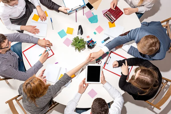 Equipo sentado detrás del escritorio, revisando informes, hablando. Vista superior — Foto de Stock