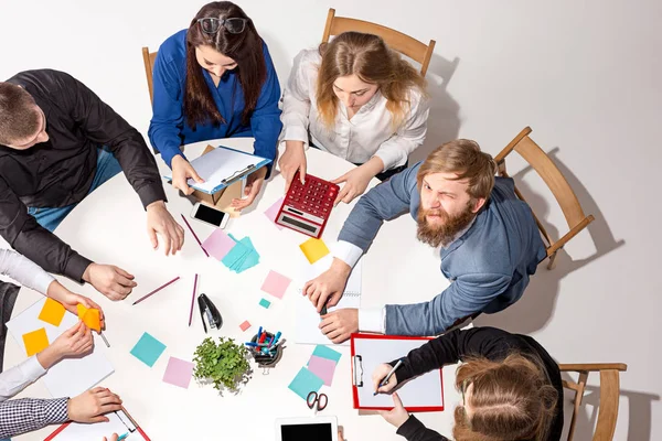 Team sitting behind desk, checking reports, talking. Top View — Stock Photo, Image