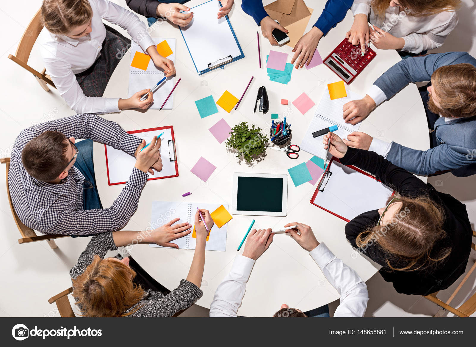 Team sitting behind desk, checking reports, talking. Top View ...