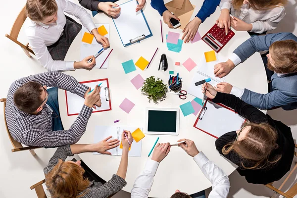 Equipo sentado detrás del escritorio, revisando informes, hablando. Vista superior — Foto de Stock