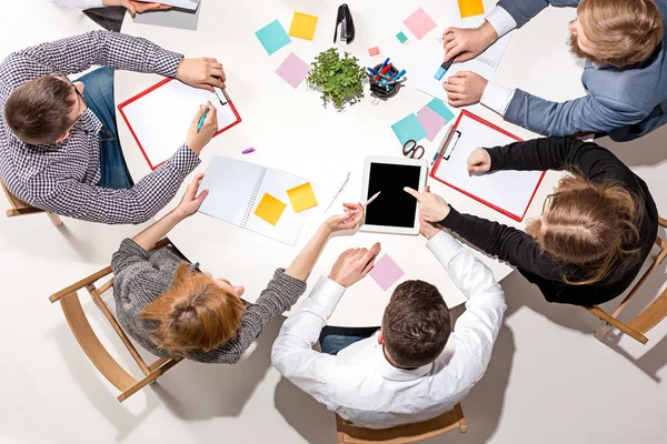 Equipo sentado detrás del escritorio, revisando informes, hablando. Vista superior — Foto de Stock