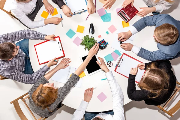 Team sitting behind desk, checking reports, talking. Top View — Stock Photo, Image