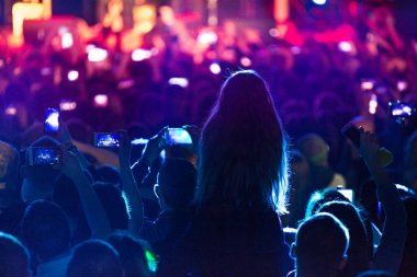 Konser siluetleri parlak sahne ışıkları önünde kalabalık. Konser bir soyut rock grubu
