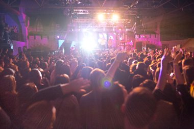 Konser siluetleri parlak sahne ışıkları önünde kalabalık. Konser bir soyut rock grubu