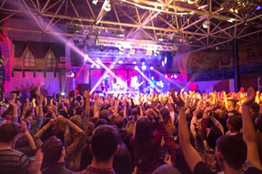 Konser siluetleri parlak sahne ışıkları önünde kalabalık. Konser bir soyut rock grubu