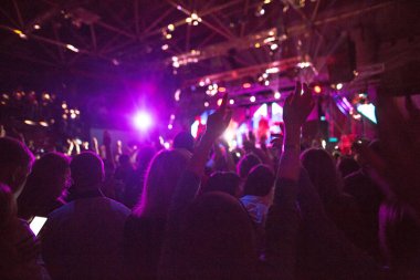 Konser siluetleri parlak sahne ışıkları önünde kalabalık. Konser bir soyut rock grubu