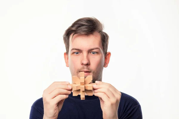 Attraktiver 25-jähriger Geschäftsmann schaut verwirrt auf Holzpuzzle. — Stockfoto