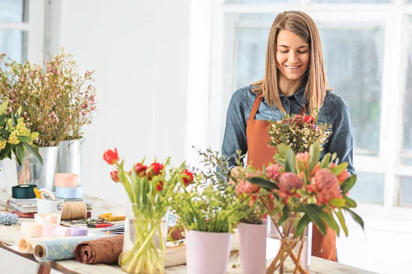 Florist at work: the female hands of woman making fashion modern bouquet of different flowers