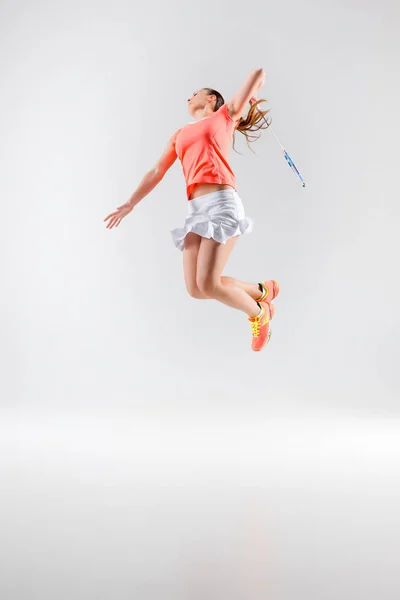 Junge Frau spielt Badminton auf weißem Hintergrund — Stockfoto