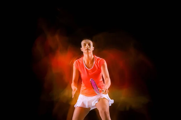 Ung kvinna spelar badminton över svart bakgrund — Stockfoto