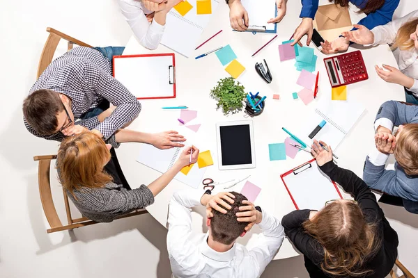 Équipe assise derrière le bureau, vérifiant les rapports, parlant. Vue du dessus — Photo